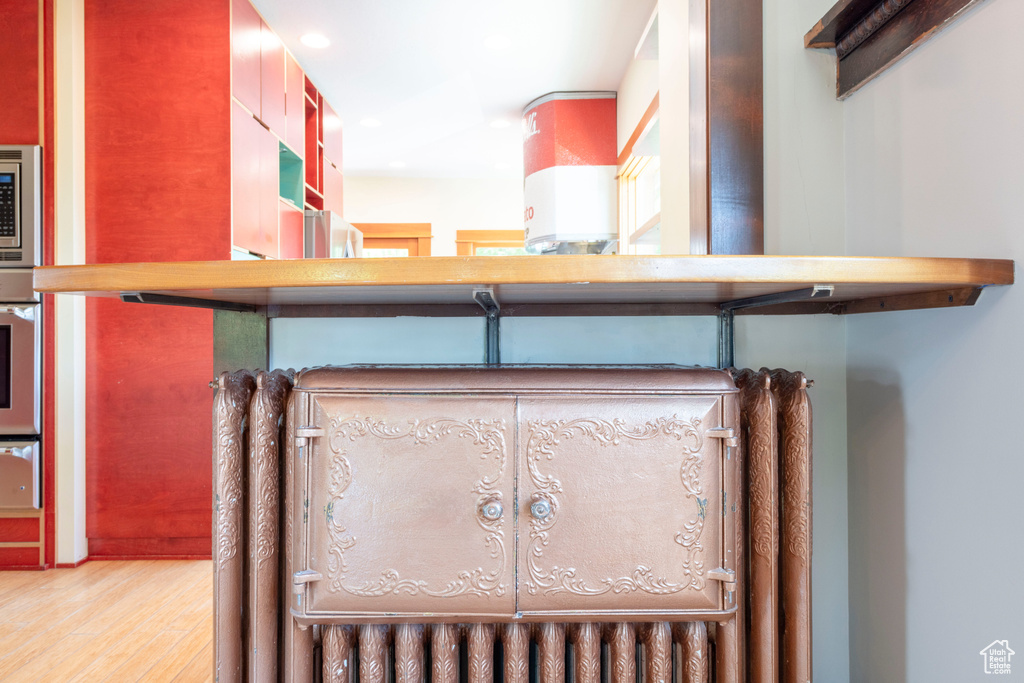 Detailed view of wood finished floors, a warming drawer, recessed lighting, and stainless steel appliances