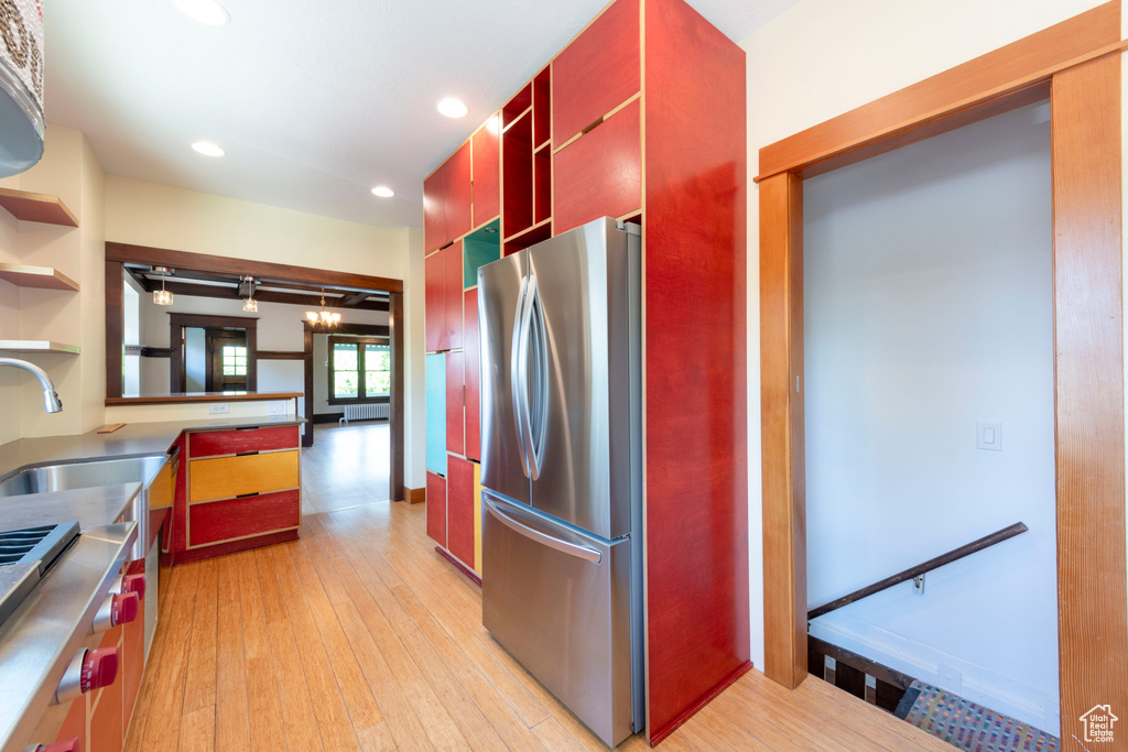 Kitchen with appliances with stainless steel finishes, a sink, light wood-style flooring, recessed lighting, and red cabinets