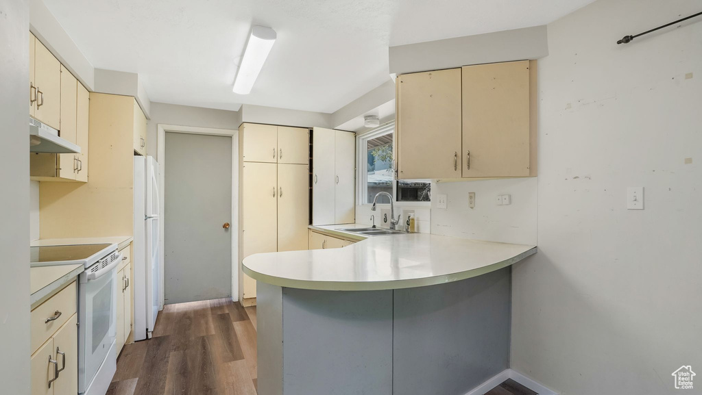 Kitchen with white appliances, cream cabinetry, a sink, and a peninsula