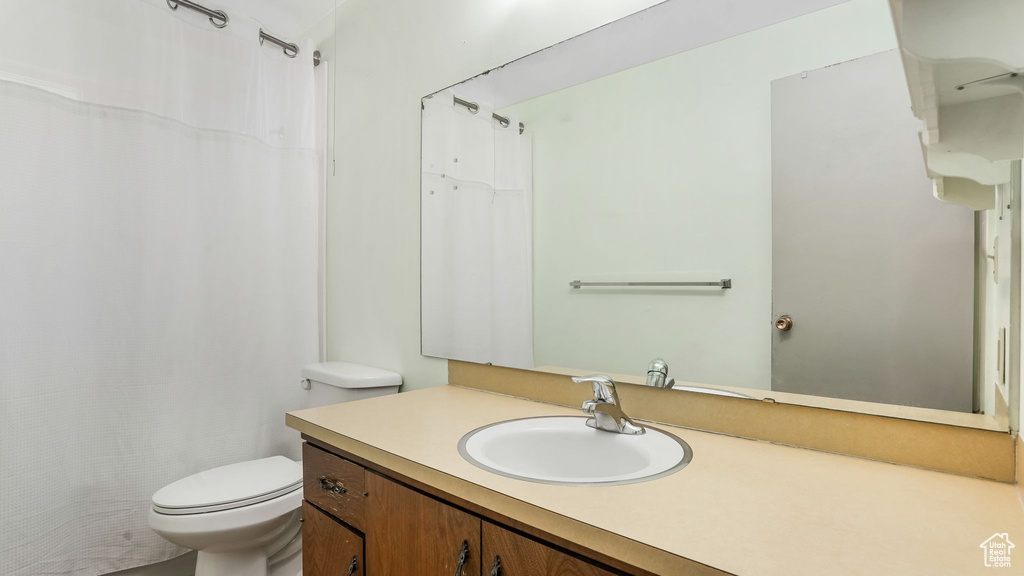 Bathroom with toilet, vanity, and a shower with curtain