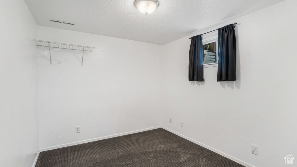 Spare room featuring baseboards and dark carpet