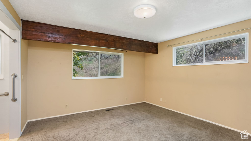 Carpeted spare room featuring baseboards