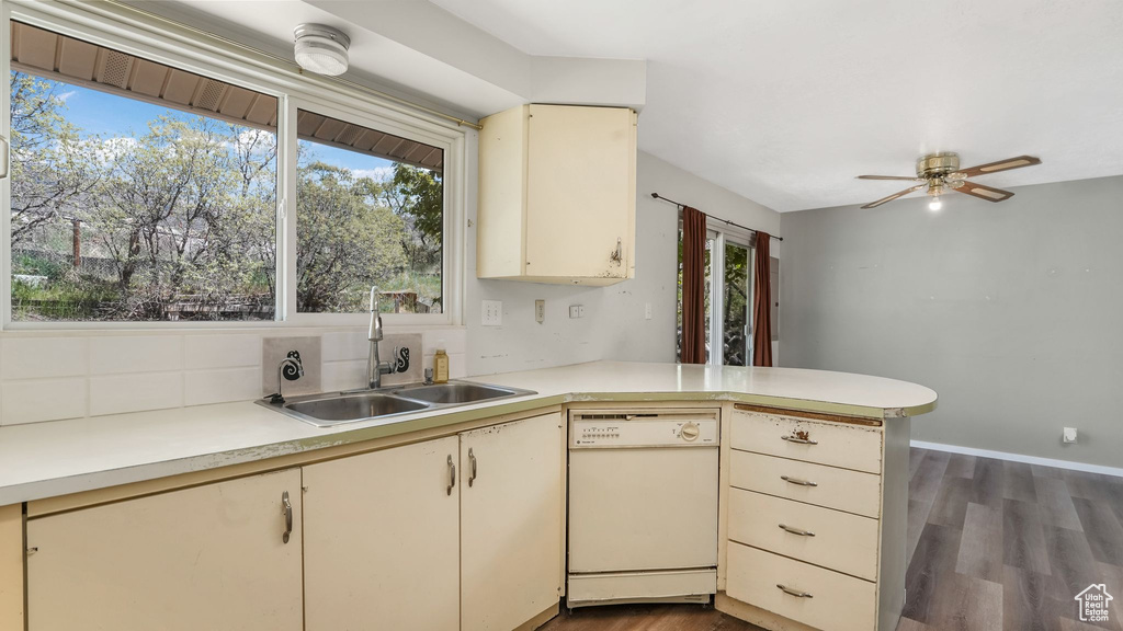 Kitchen featuring dishwasher, a sink, cream cabinetry, a peninsula, and light countertops