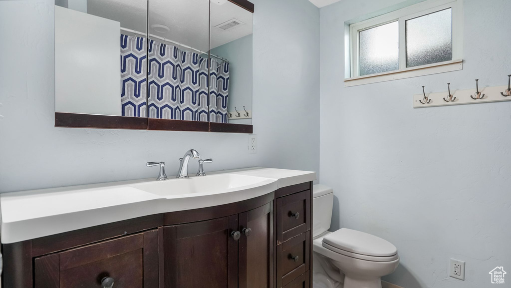 Full bathroom with toilet, vanity, and curtained shower