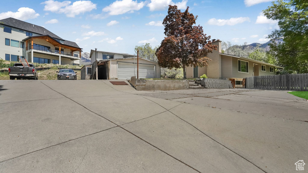 View of front of property featuring fence, a mountain view, and an outbuilding
