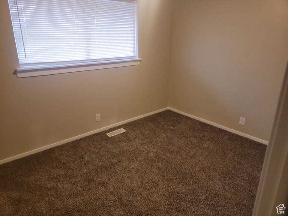 Unfurnished room with dark carpet and baseboards