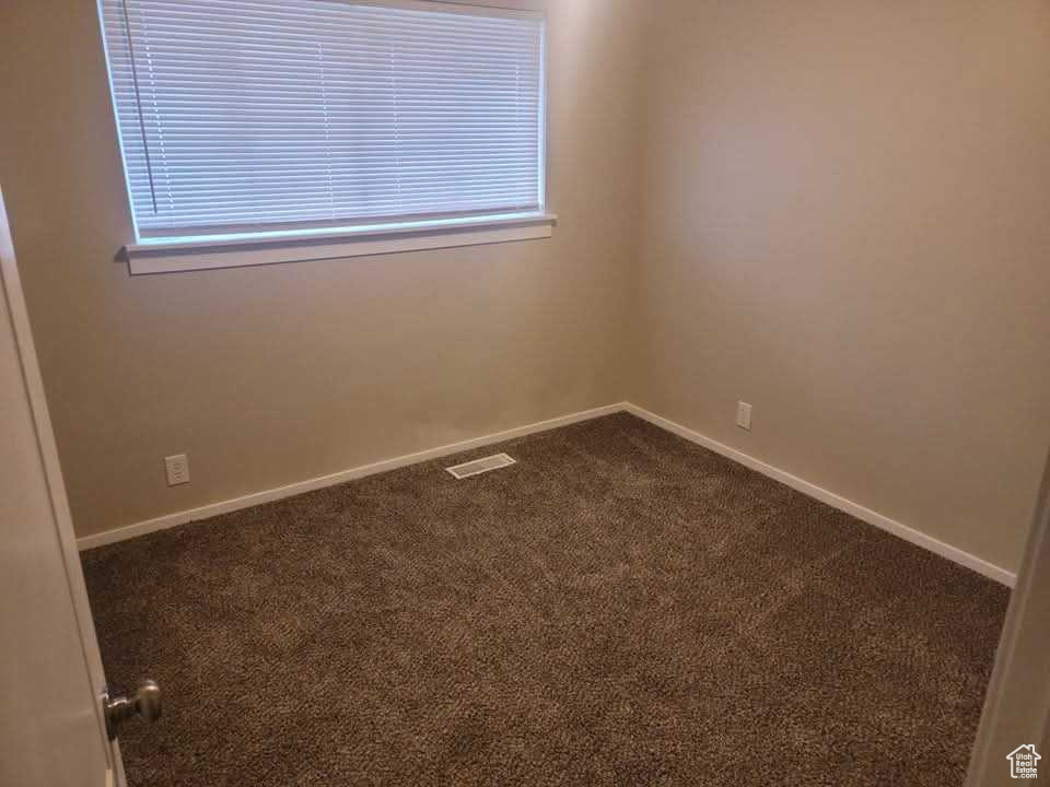 Spare room with dark carpet and baseboards
