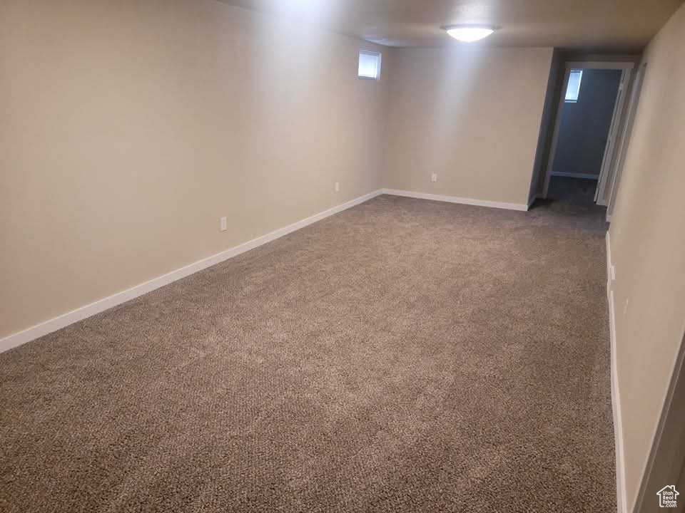 Basement featuring dark colored carpet and baseboards