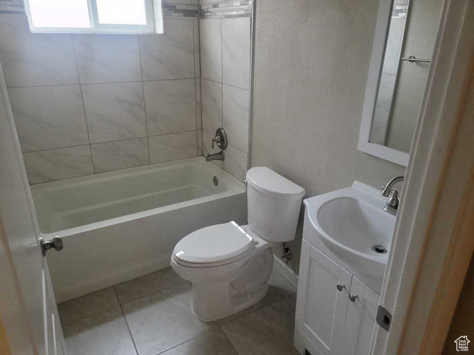 Bathroom with toilet, vanity, tile patterned floors, and shower / tub combination