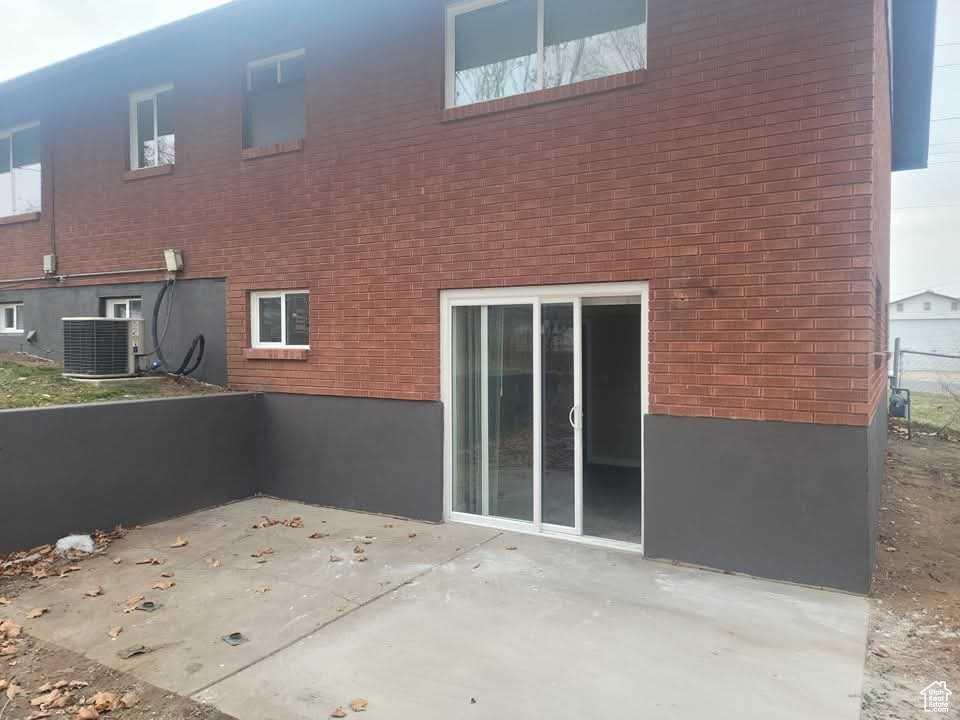 Rear view of property featuring a patio area, central air condition unit, and brick siding