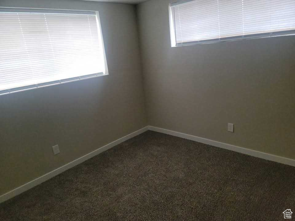 Unfurnished room featuring dark carpet and baseboards