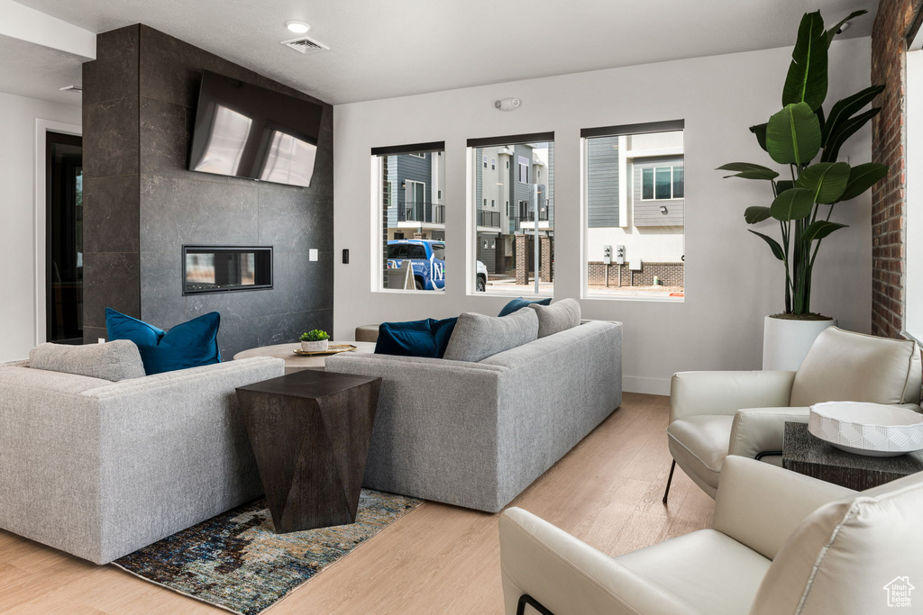 Living area with light wood-style floors, a tiled fireplace, and baseboards