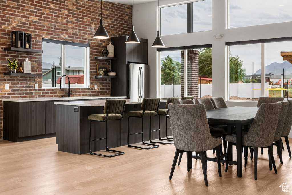 Dining space featuring light wood-style floors, a mountain view, a high ceiling, and brick wall