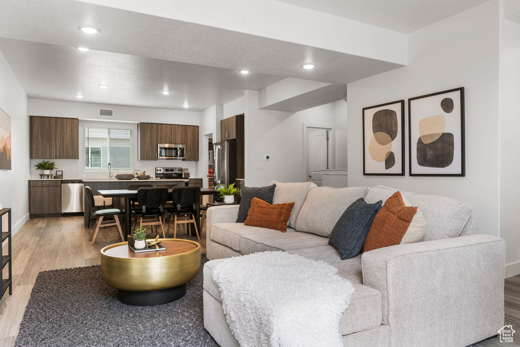 Living area with light wood-type flooring and recessed lighting
