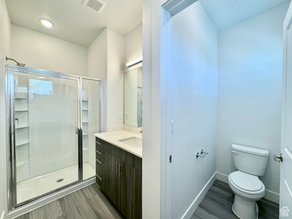 Bathroom with wood finished floors, a stall shower, and toilet