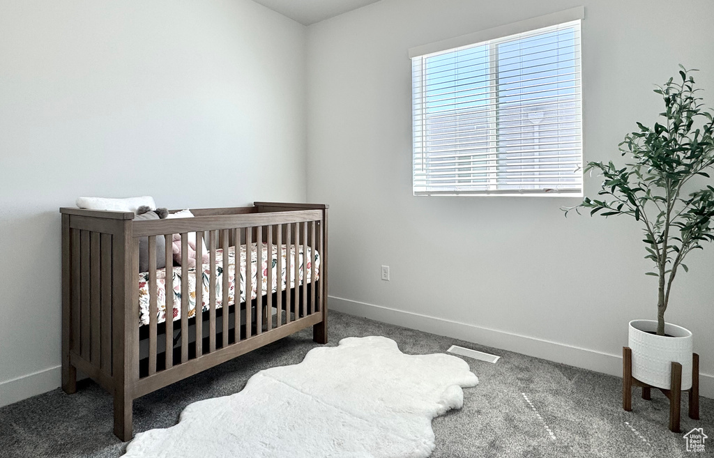 Carpeted bedroom featuring baseboards and a crib