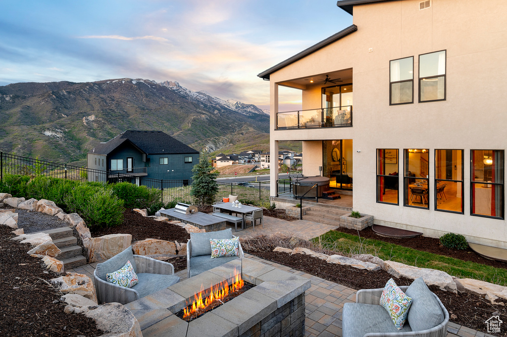 View of yard featuring a balcony, an outdoor fire pit, a patio, fence, and a mountain view