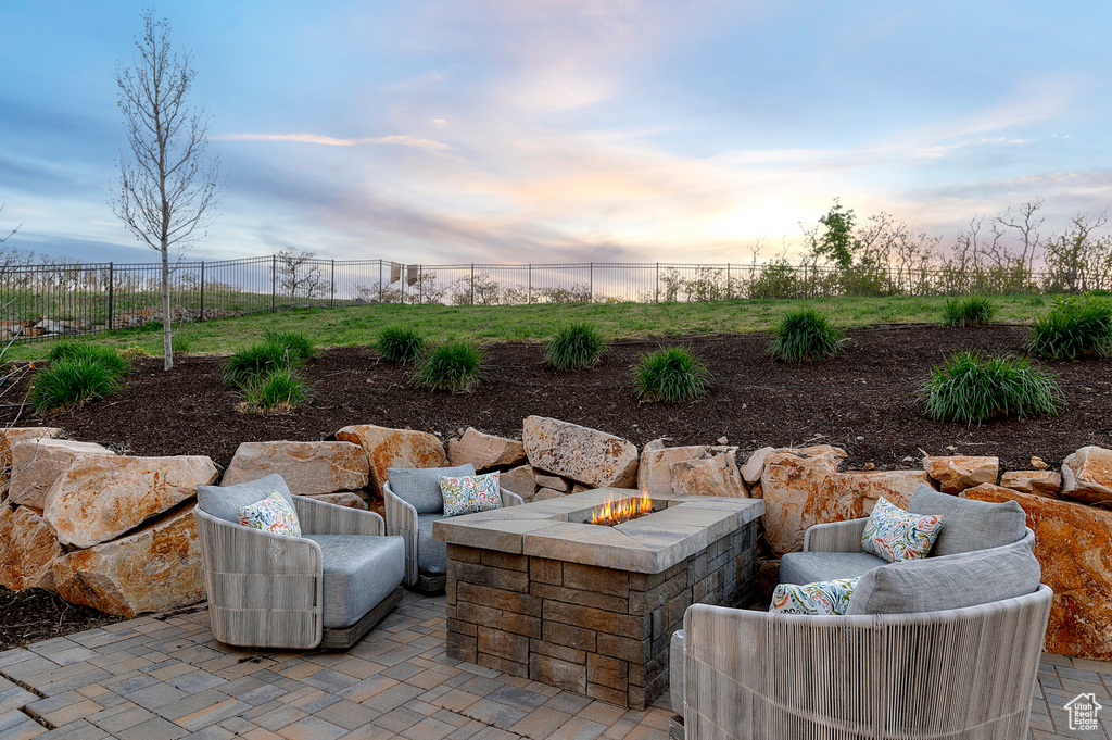Patio terrace at dusk featuring fence and an outdoor living space with a fire pit