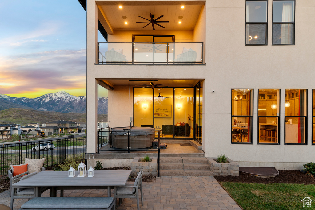 Back of house featuring a balcony, a hot tub, a patio, ceiling fan, and fence