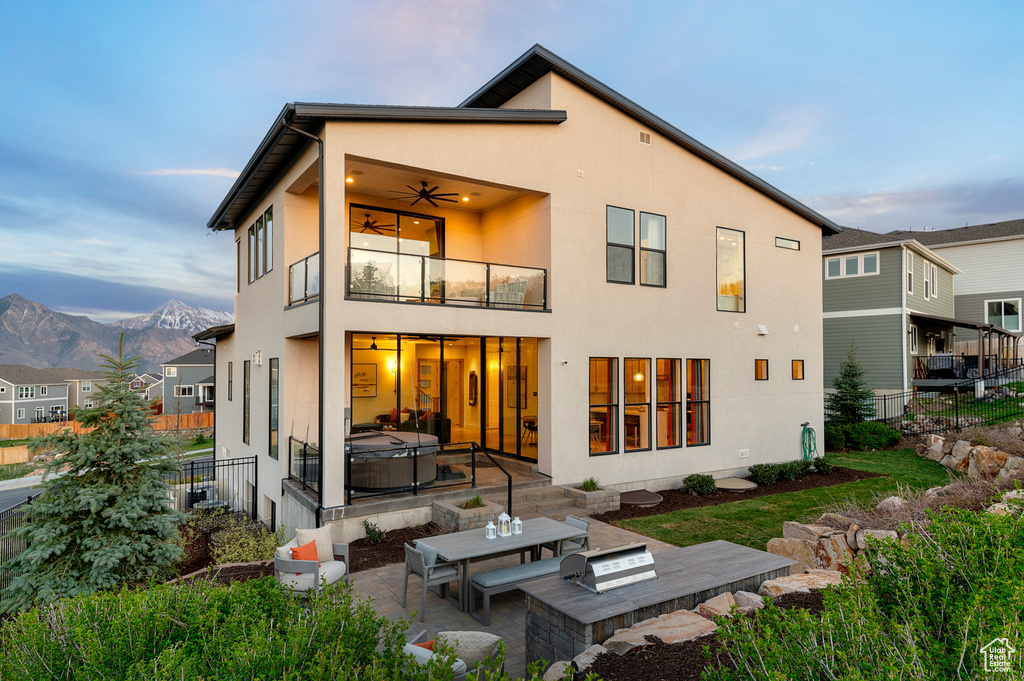 Back of house with a balcony, a patio area, a hot tub, and stucco siding