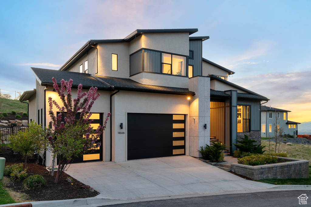 Contemporary home with a garage, driveway, stucco siding, and fence