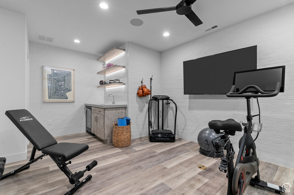 Exercise room with a ceiling fan, light wood-style flooring, recessed lighting, and bar with sink