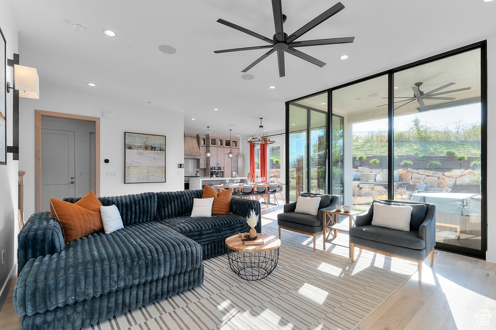 Living room featuring a ceiling fan, light wood finished floors, recessed lighting, and a wall of windows