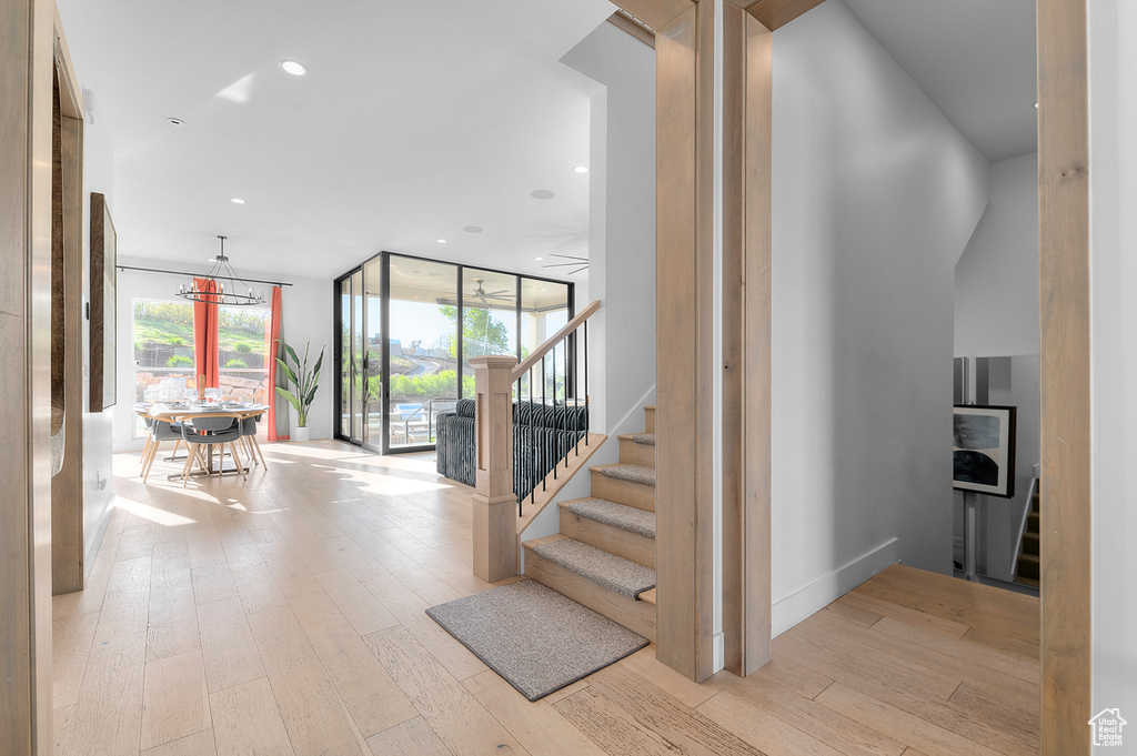 Stairway featuring wood finished floors, a wall of windows, and recessed lighting