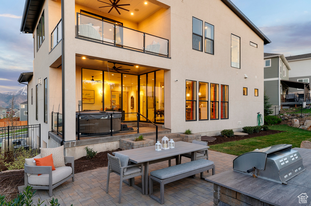Rear view of house with a hot tub, a patio, a balcony, and fence