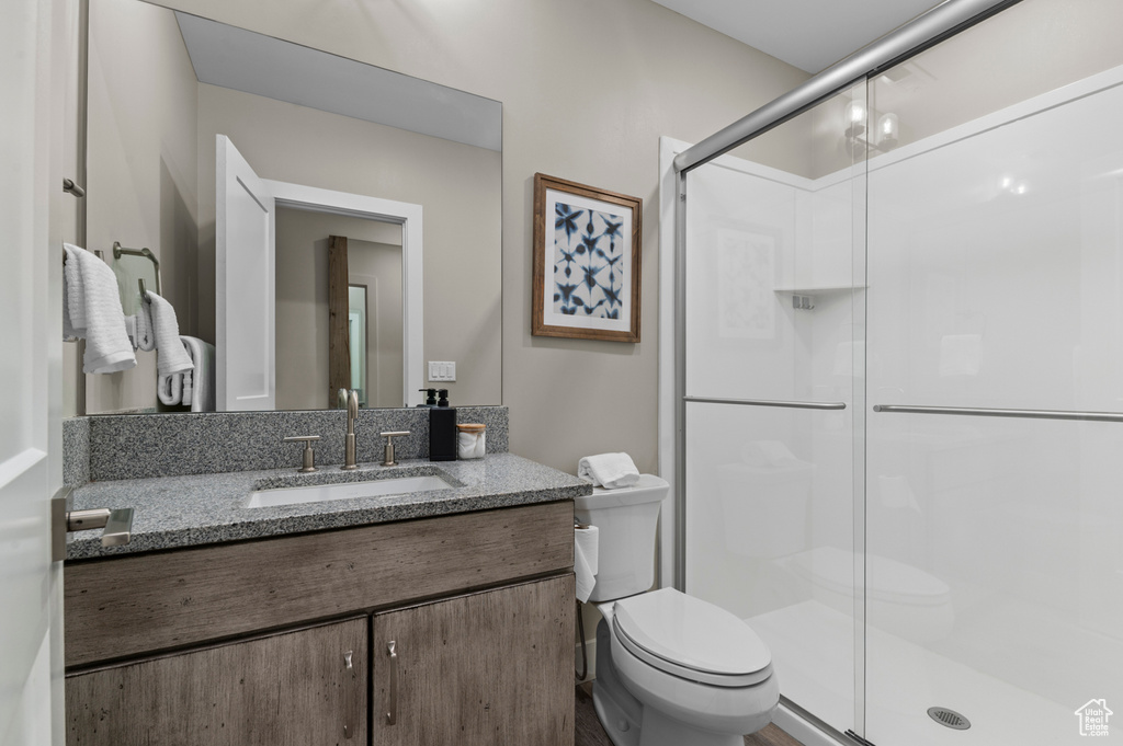 Bathroom with toilet, a stall shower, and vanity