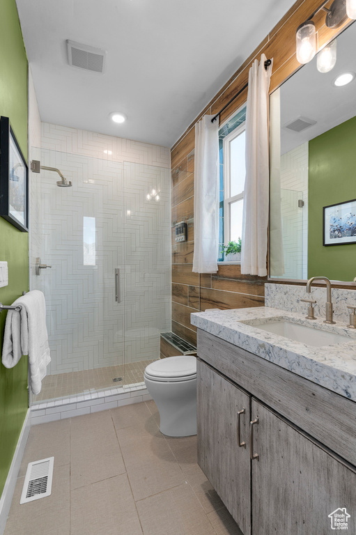 Full bathroom featuring toilet, a stall shower, vanity, and tile patterned floors