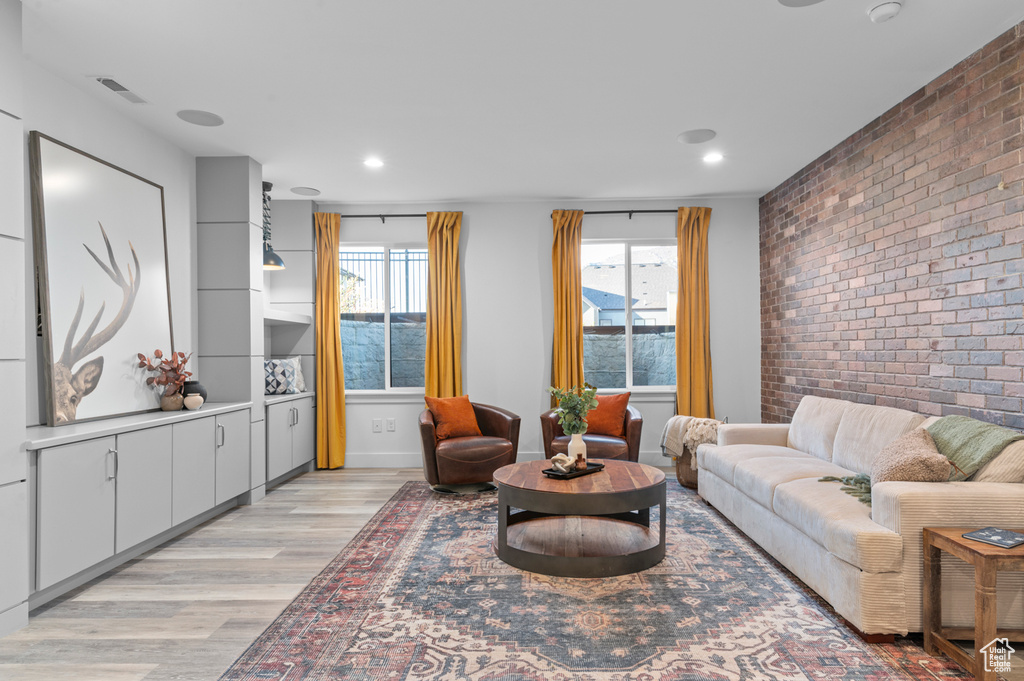 Living area with brick wall, light wood finished floors, and recessed lighting