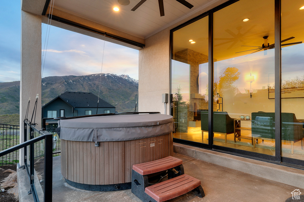 View of patio featuring a hot tub, a mountain view, ceiling fan, and fence