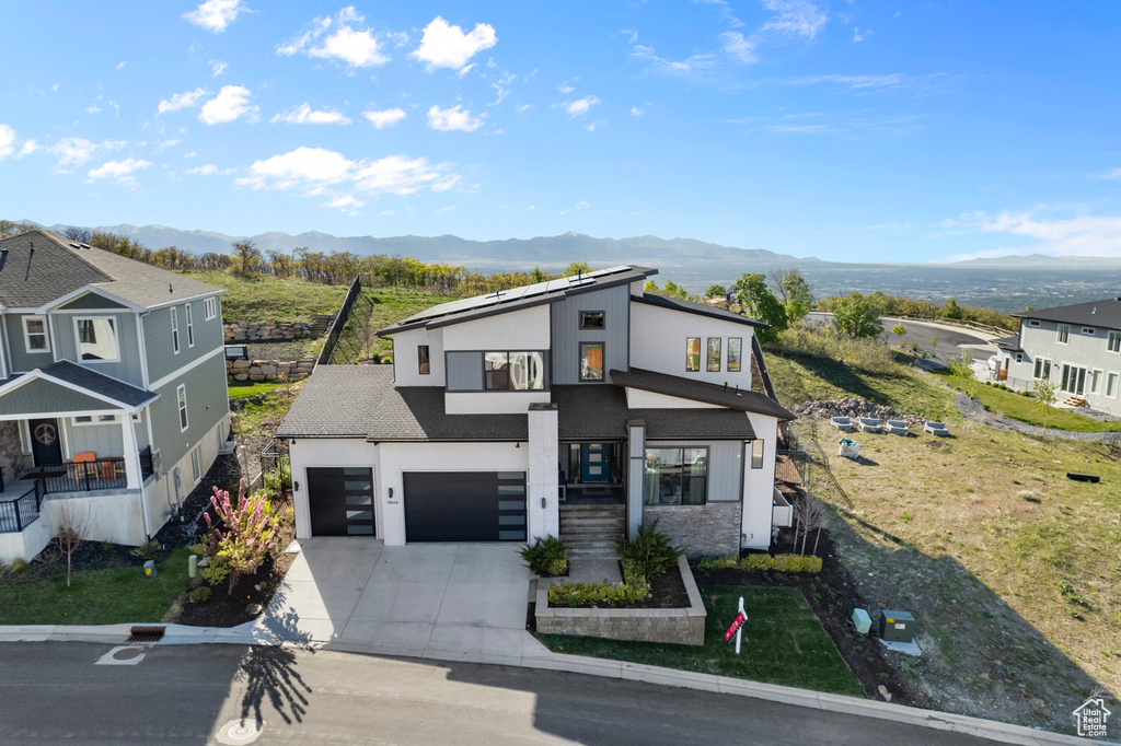 Contemporary house featuring concrete driveway, stucco siding, a mountain view, and an attached garage