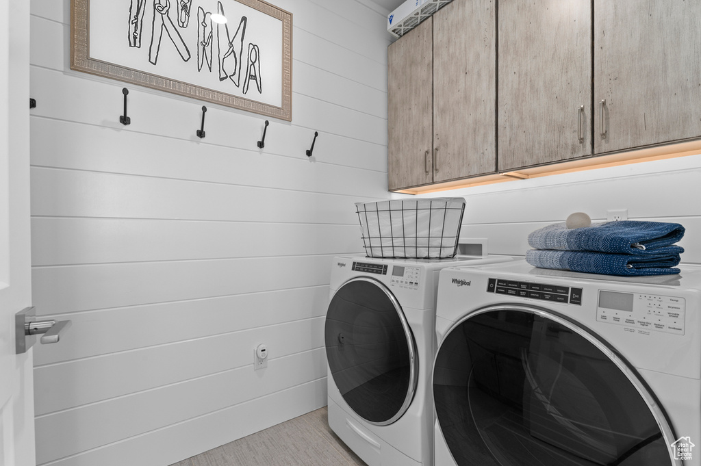 Laundry area featuring cabinet space, washing machine and clothes dryer, and wooden walls