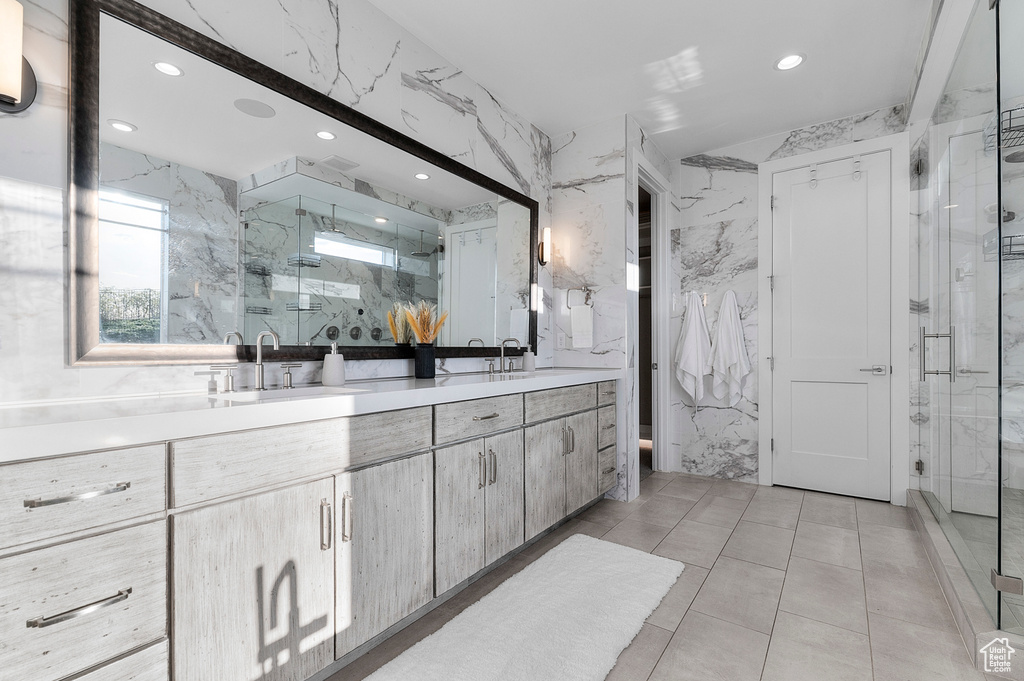 Bathroom with a marble finish shower, double vanity, and recessed lighting