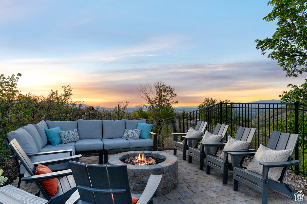 Patio terrace at dusk with an outdoor living space with a fire pit and fence