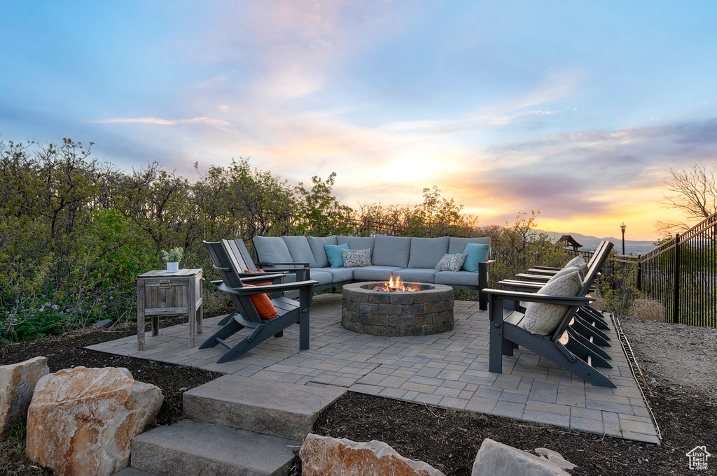 Patio terrace at dusk featuring a fire pit and fence