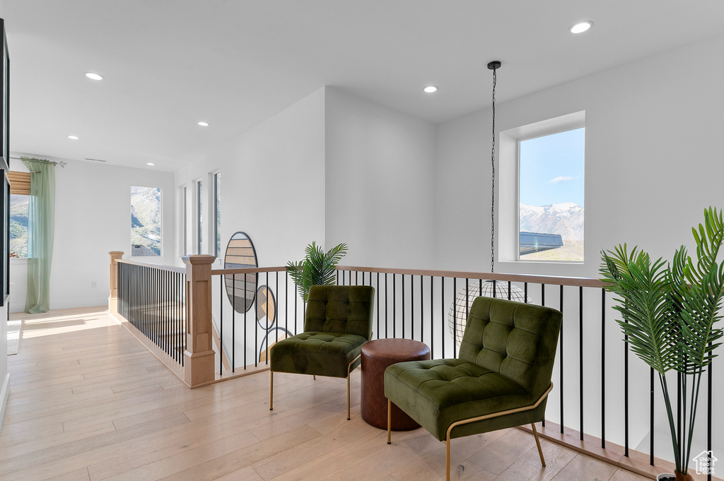 Sitting room with recessed lighting, light wood-style floors, and an upstairs landing