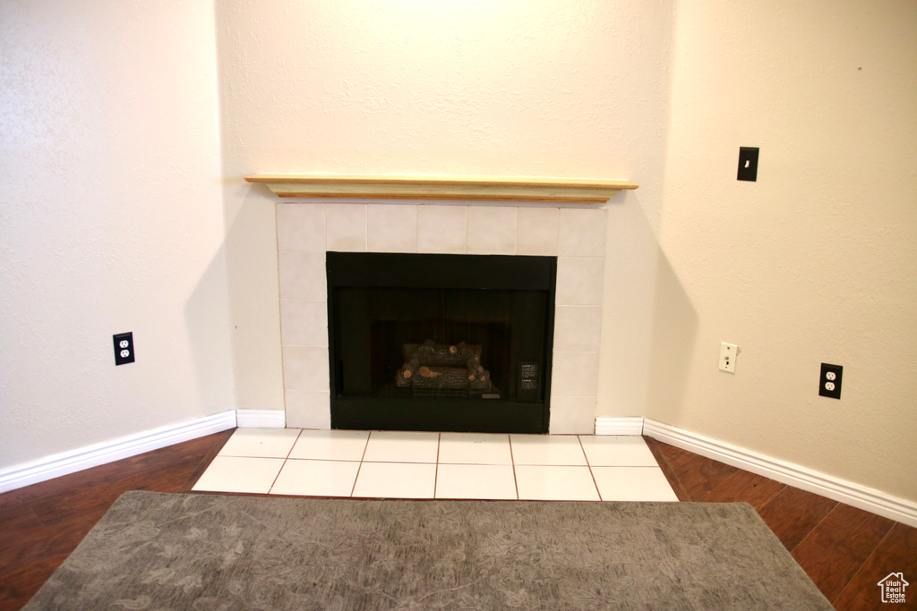 Detailed view of wood finished floors, a tiled fireplace, and baseboards