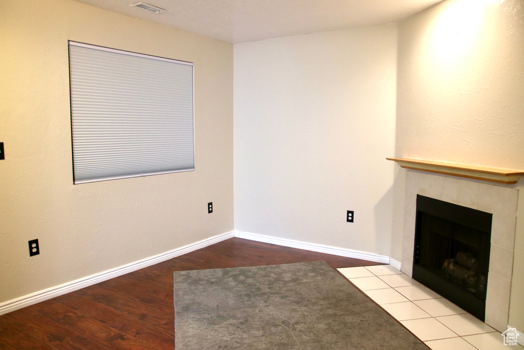 Unfurnished living room with a fireplace, wood finished floors, and baseboards