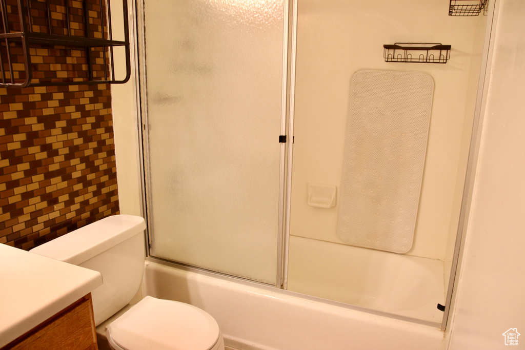Full bath with toilet, vanity, and combined bath / shower with glass door