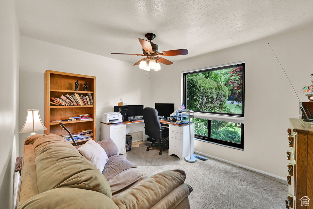Carpeted home office with baseboards, ceiling fan, and a textured ceiling