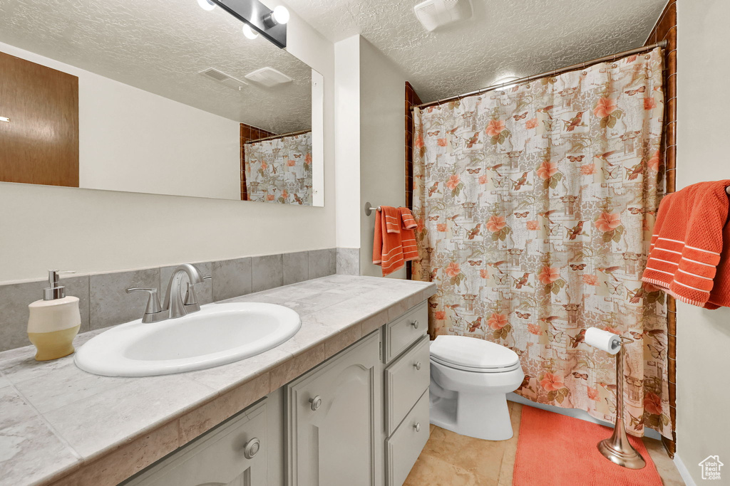 Full bath with vanity, toilet, and a textured ceiling
