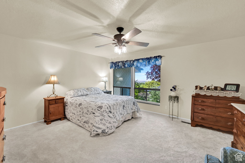 Bedroom with light colored carpet, baseboards, and a ceiling fan