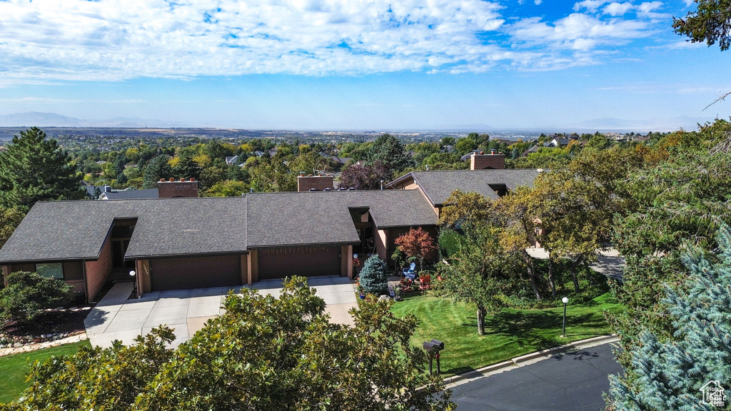 View of front of home featuring a garage, driveway, a chimney, and a shingled roof