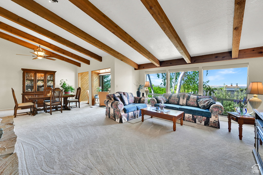 Living room with light colored carpet, plenty of natural light, beamed ceiling, and a ceiling fan