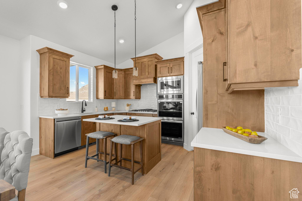 Kitchen featuring appliances with stainless steel finishes, a center island, a breakfast bar area, decorative backsplash, and a sink
