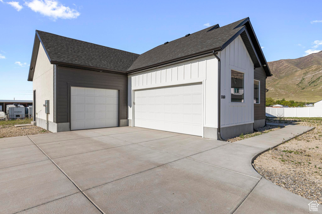 Garage with driveway, a mountain view, and fence