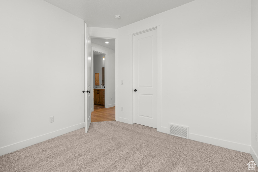 Empty room featuring light carpet, baseboards, recessed lighting, and a smoke detector